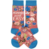 A pair of colorful woven socks from our Mother's Day Collection displaying unique hand illustrated designs of flowers with a fun mom-themed sentiment that reads "Mommin' Ain't Easy." Socks feature a one size fits most design made with cotton, nylon, and spandex. Our Mommin' Ain't Easy socks come with a header card and a clear plastic hanger for display. A fun Mother's Day gift and accessory perfect for everyday self-expression.